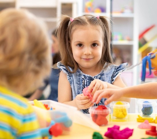 Dziewczynka bawiąca się plasteliną przy stoliku w sali żłobka