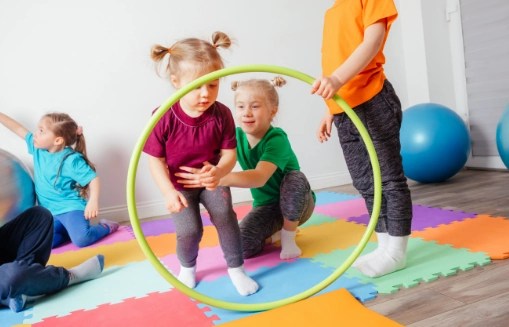 Dzieci bawią się hula-hop na kolorowych matach w sali gimnastycznej